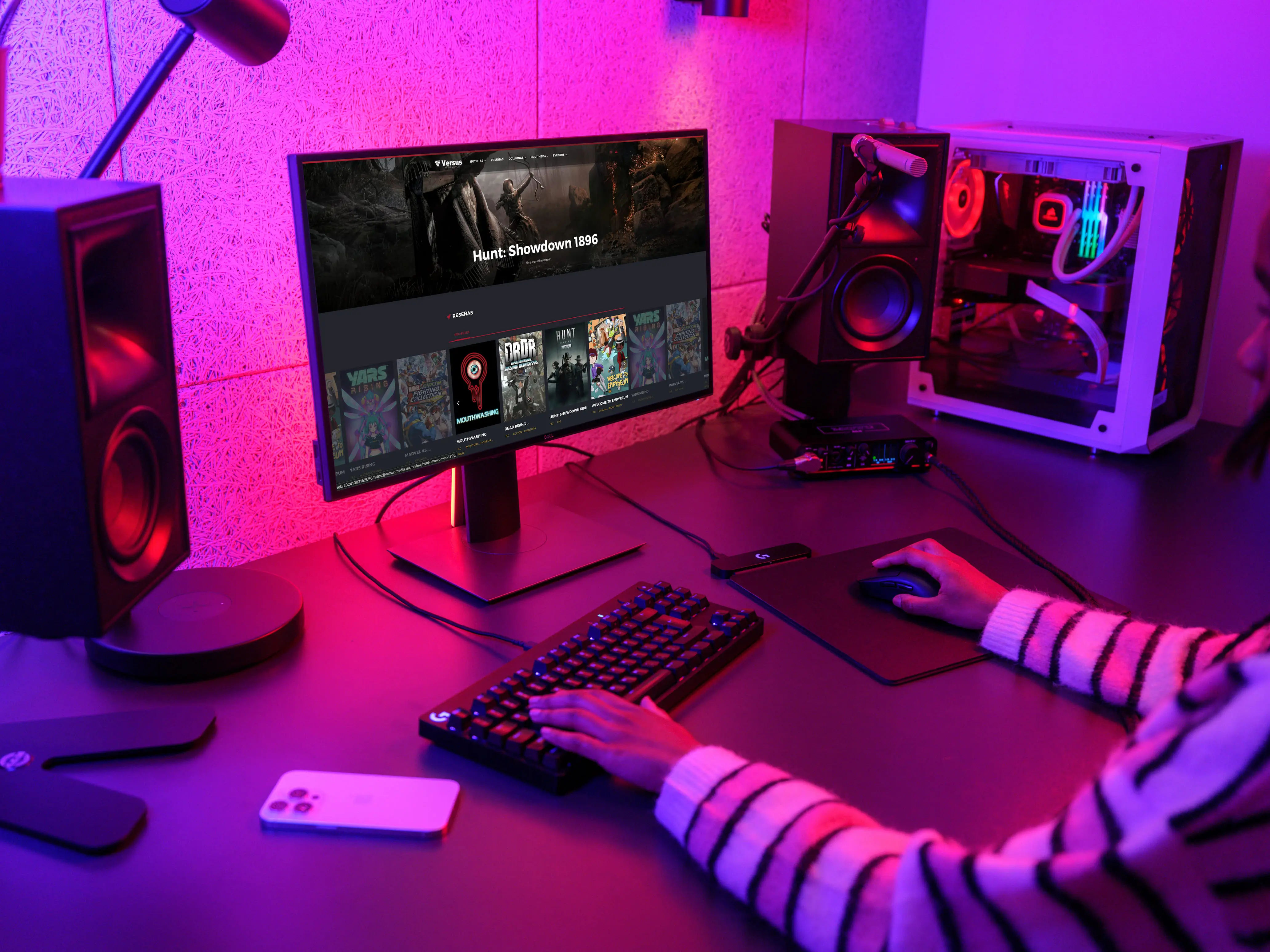 Photograph of a gaming PC setup with the versusmedia.mx website open on the monitor.